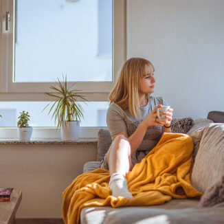 Young adult woman relaxing on the couch while enjoying a cup of coffee
