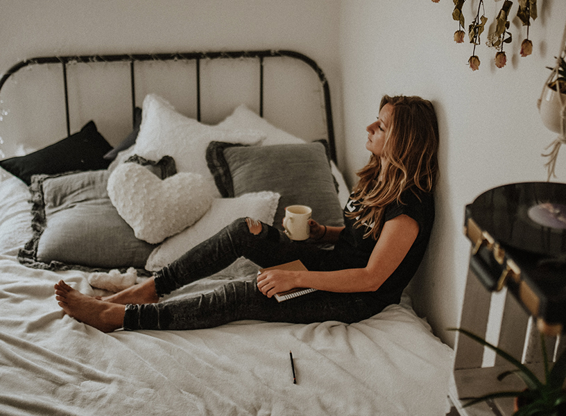 Young woman relaxing in bed with enjoying a cup of coffee