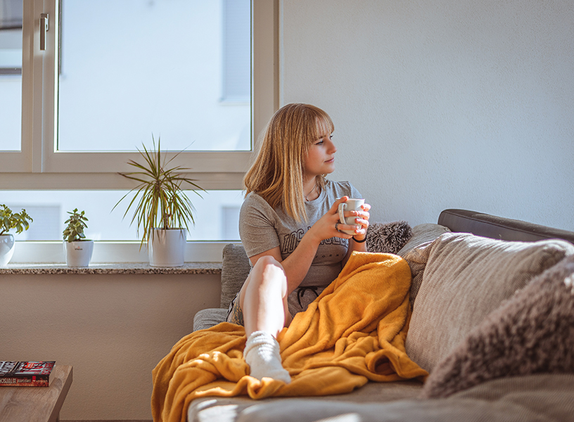 Young adult woman relaxing on the couch while enjoying a cup of coffee