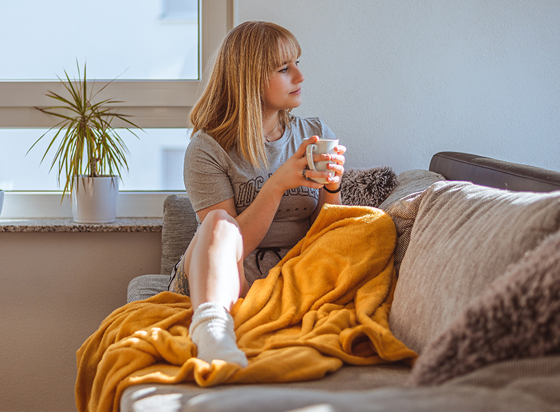 Young adult cozy on the couch with a cup of coffee